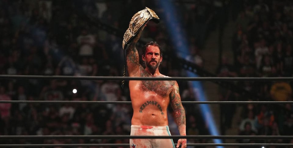 CM Punk bleeding, holding his AEW Championship belt over his head with one arm.