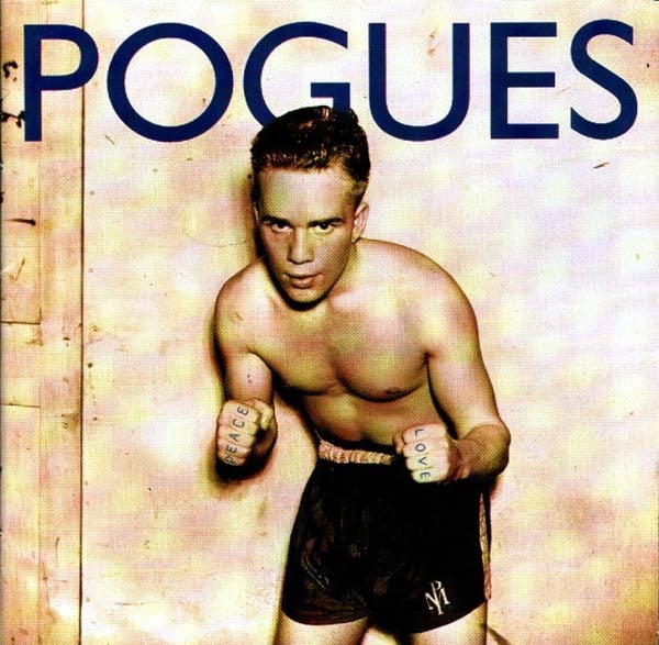 A sepia-toned photo of a young white boxer, facing the camera, in boxing pose but no boxing gloves. He has short dark hair and wears only boxer shorts. The photo looks as if it's from the 40s or 50s. He has "Peace" and "Love" tattooed on his fingers. This means his one fist was photoshopped to add a sixth finger.