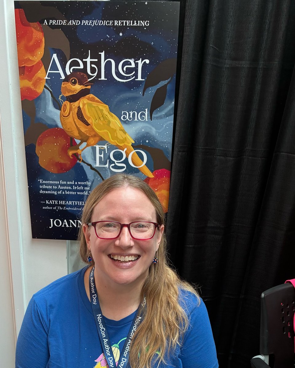 Joanne smiling in front of a blowup of her book cover