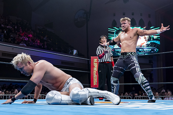 Will Ospreay delivers a Rainmaker pose while standing over a fallen Kazuchika Okada.