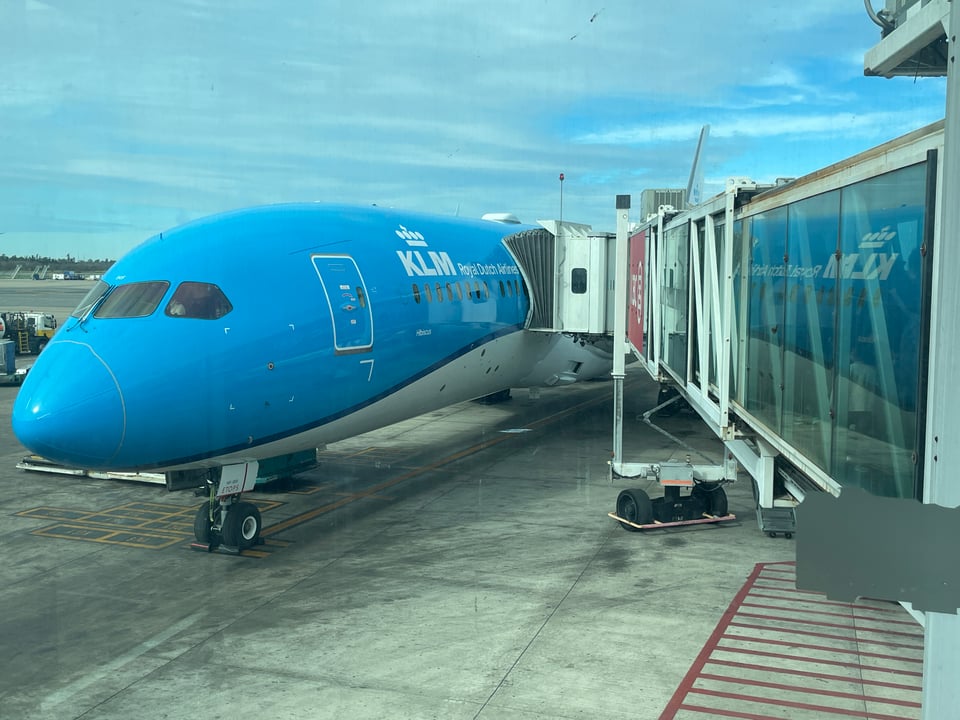 A KLM airplane at the airport with the boarding tunnel attached.