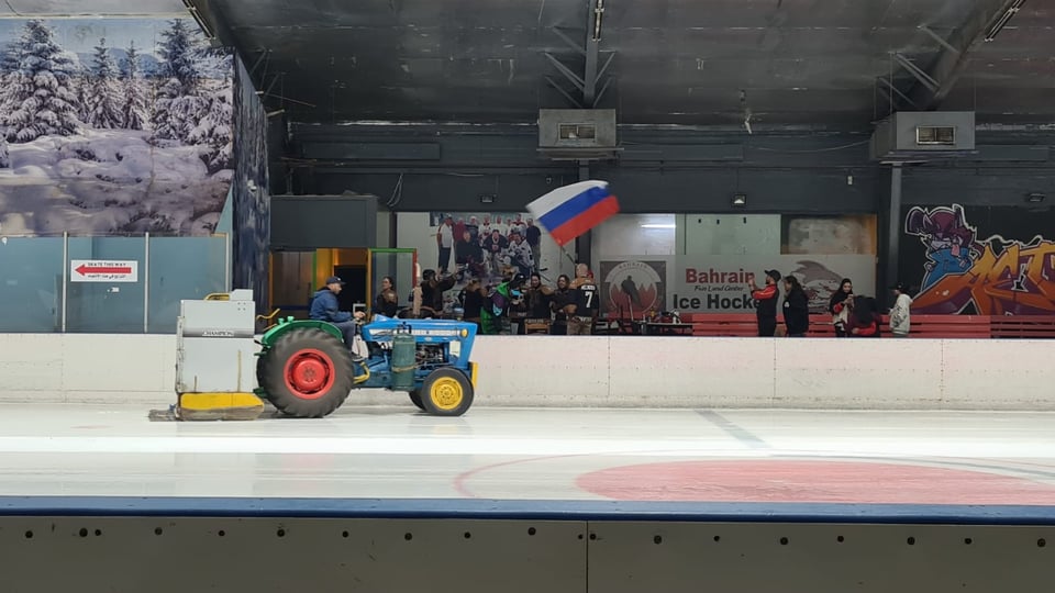 Russian team in pre-match huddle waving a flag. Zamboni machine crossing rink in foreground.