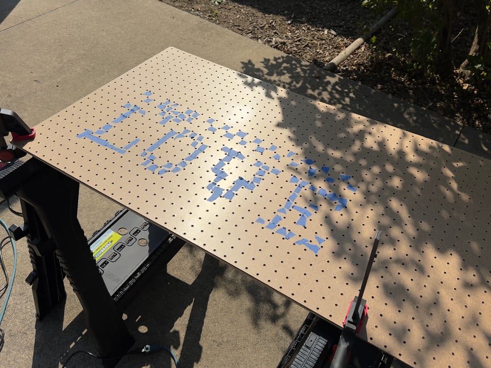 Pegboard with blue tape that spells out "love" laying on workhorses outside