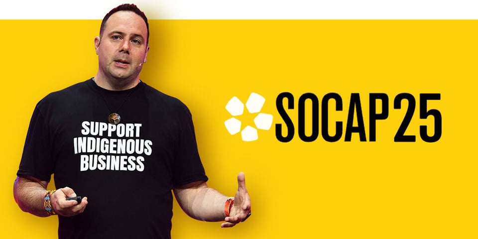 Indigenous man with short dark hair wearing a black t-shirt stands against a yellow background, with the logo for SOCAP25 on the right hand side.