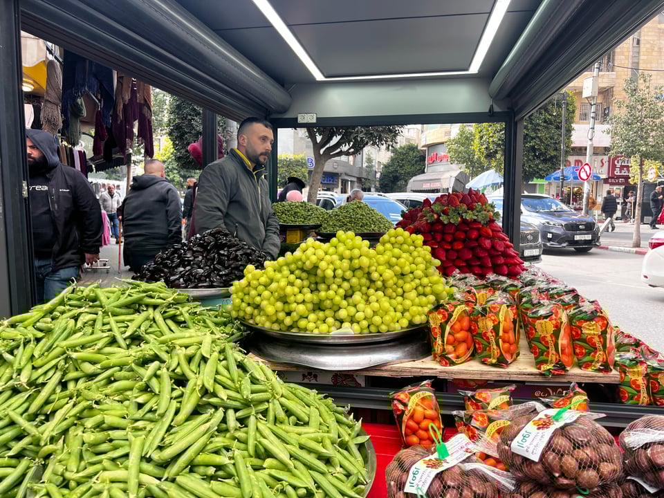 Grapes, beans, bags of chestnuts, and bags of oranges at a fruit stand