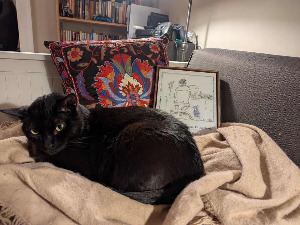 The black cat is curled up in front of the award plaque. You can now see Le Guin's sketch of herself sitting in front of a computer.