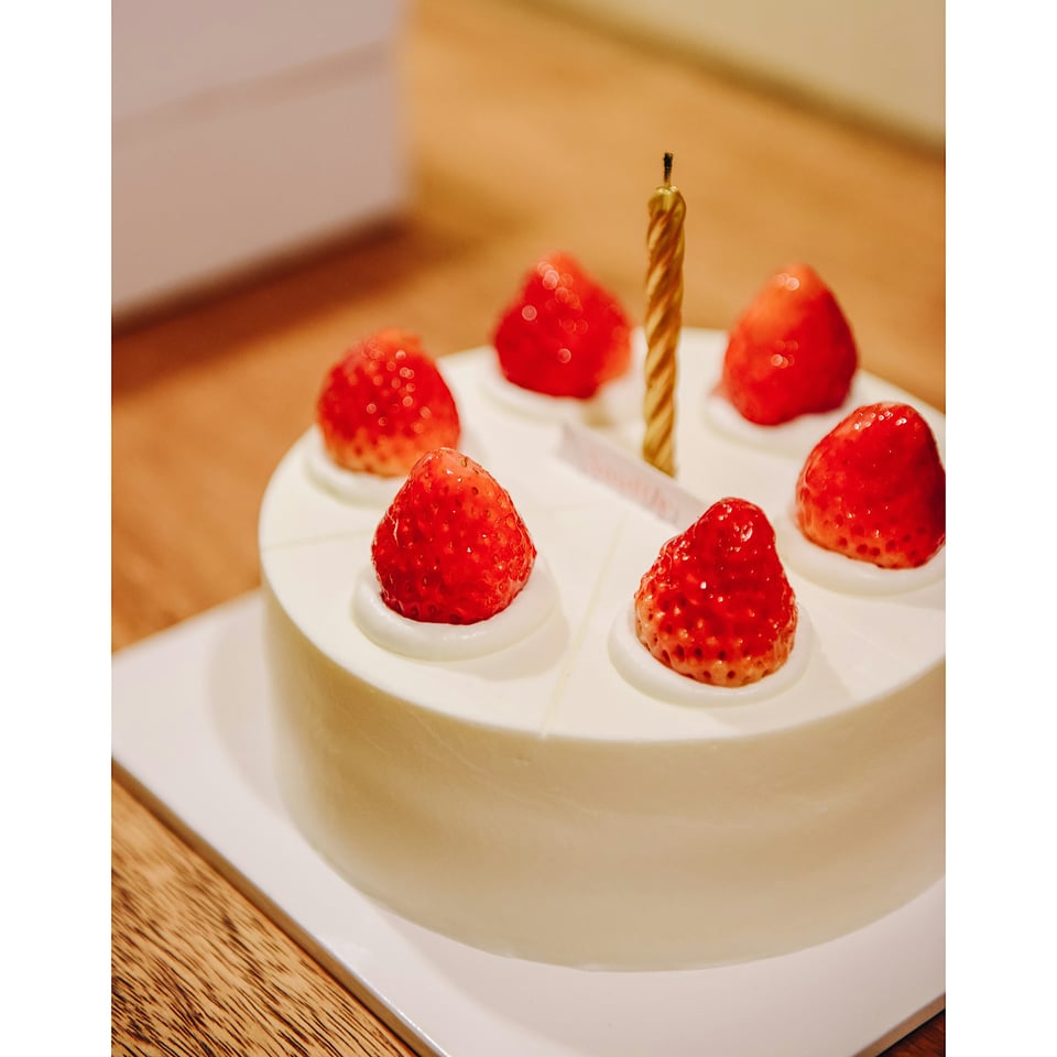 A white cake with six strawberries and one candle
