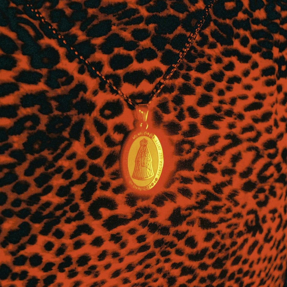 track art: a glowing saint pendant against a cheetah-print top