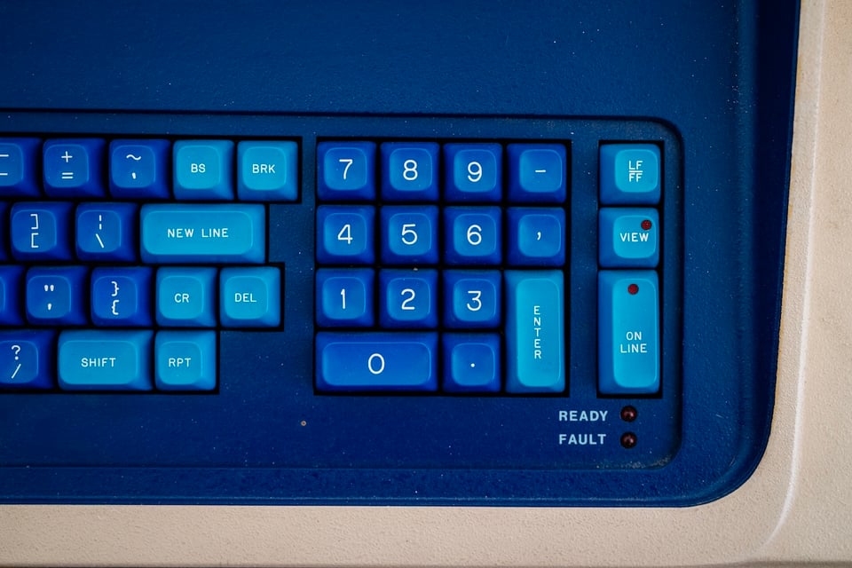 A photograph of half of a biege and blue computer keyboard