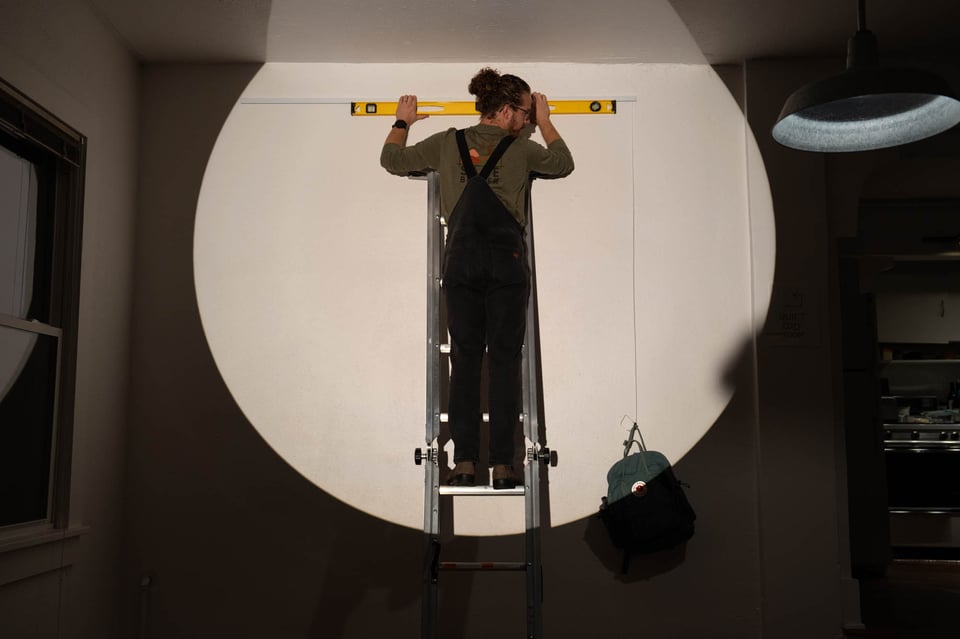 A well lit man on a ladder.