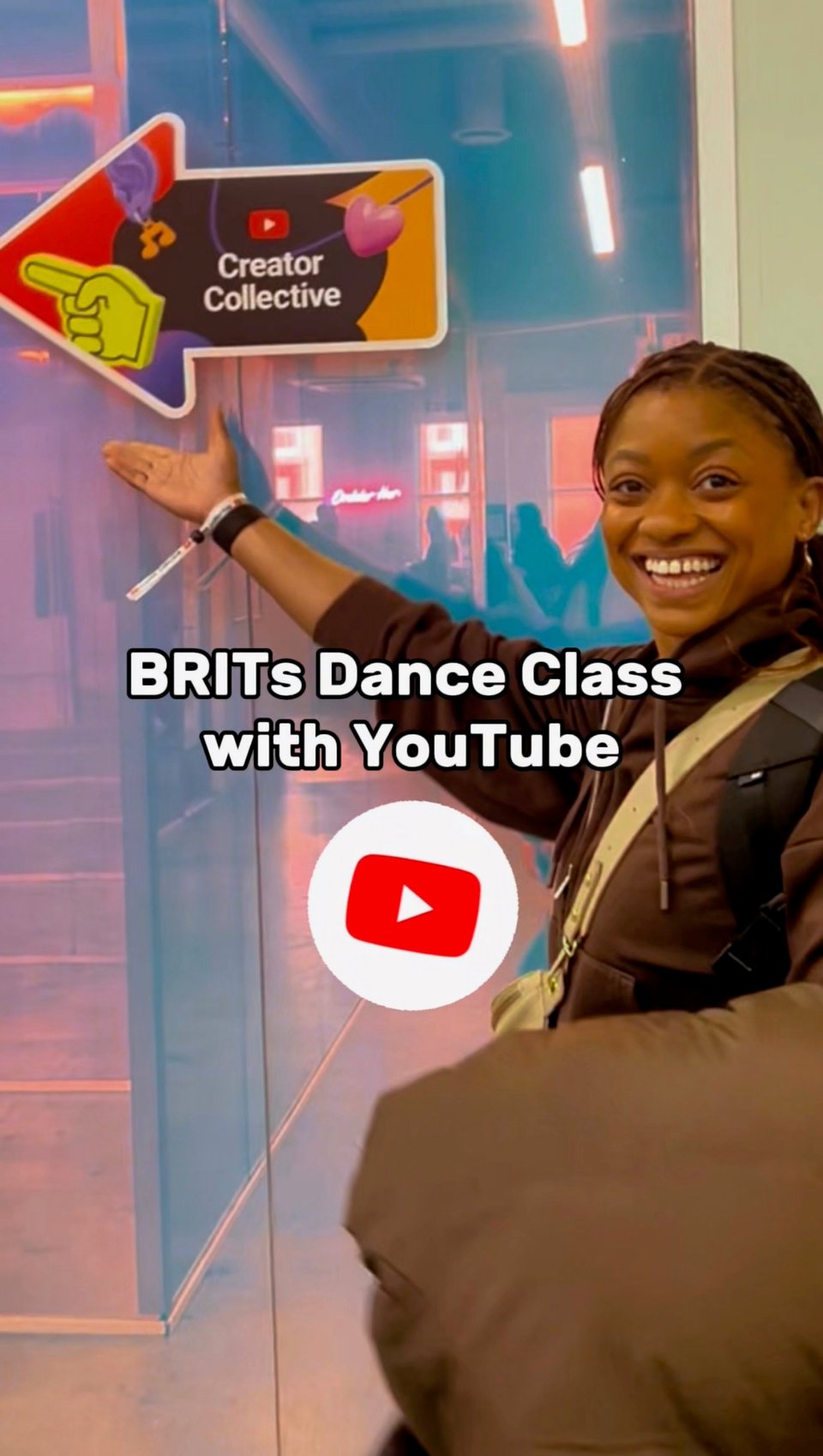 I’m standing beside a glass wall and pointing toward a sign that says “Creator Collective,” smiling widely. Overlaid text reads “BRITs Dance Class with YouTube,” with a YouTube logo beneath.