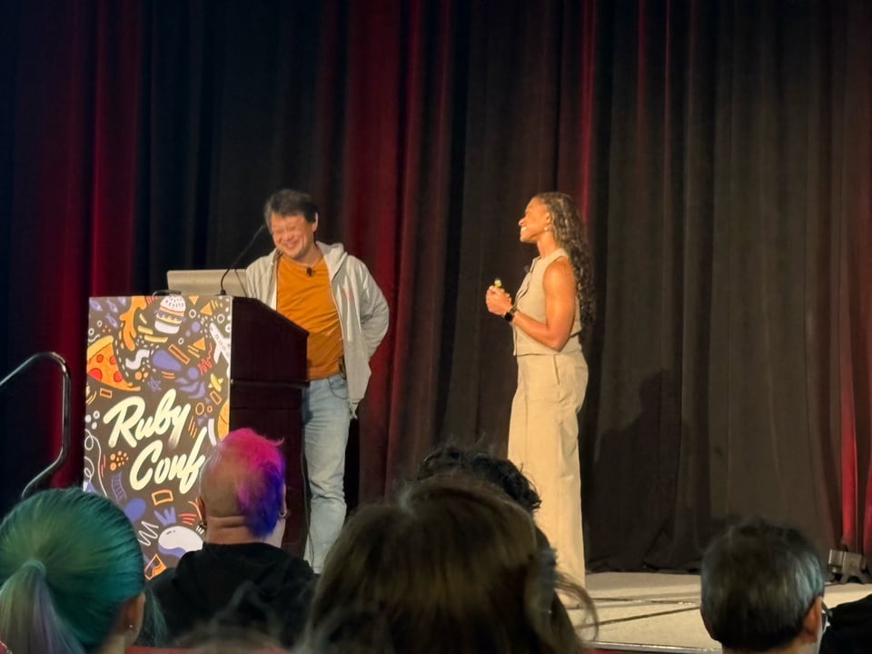 A photo of Matz and I on stage. Matz is at the podium and I am on the side looking on admiringly.