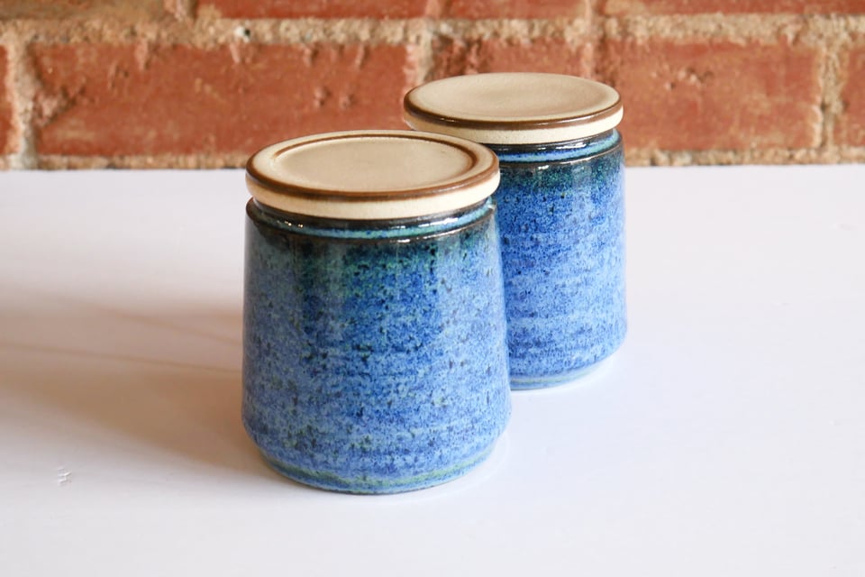 two jars with textured blue sides and cream colored lids