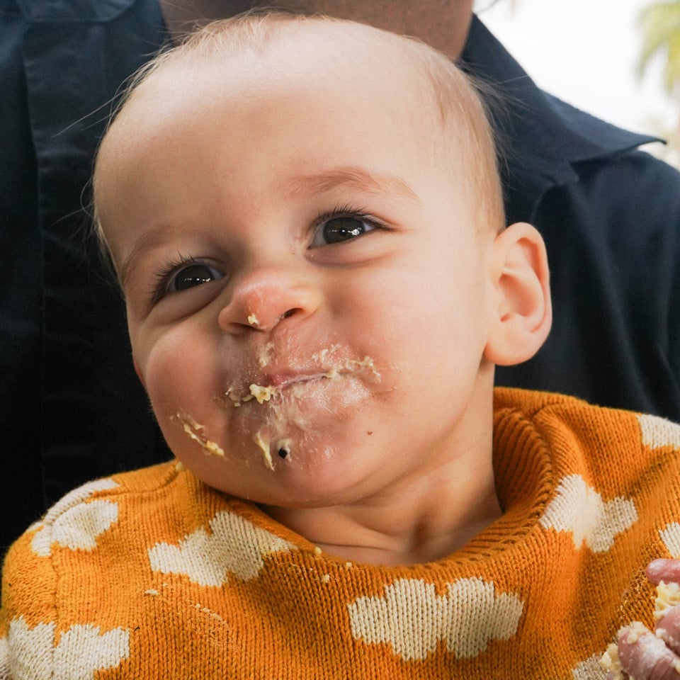 A baby smiles with his face smeared with cake frosting