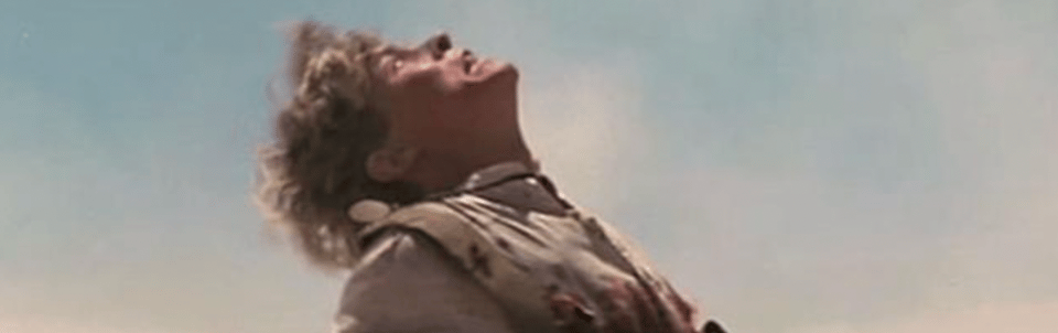 Mark Lee, a white man with blonde hair, as Archie in Gallipoli. Gunshots and blood mar his Australian infantry uniform. He's upright, running, but already dead.