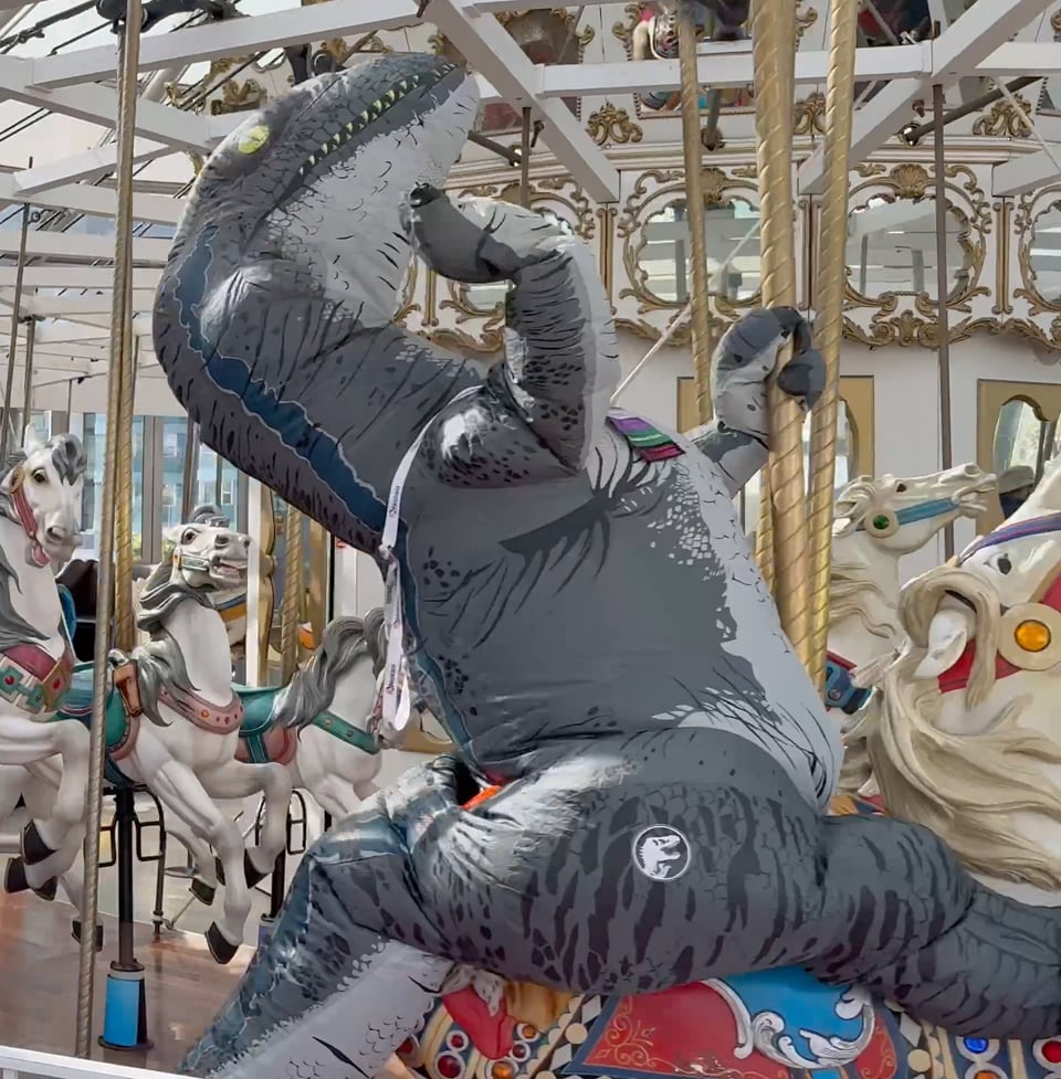 A rider on the carousel wearing a full-body raptor costume.