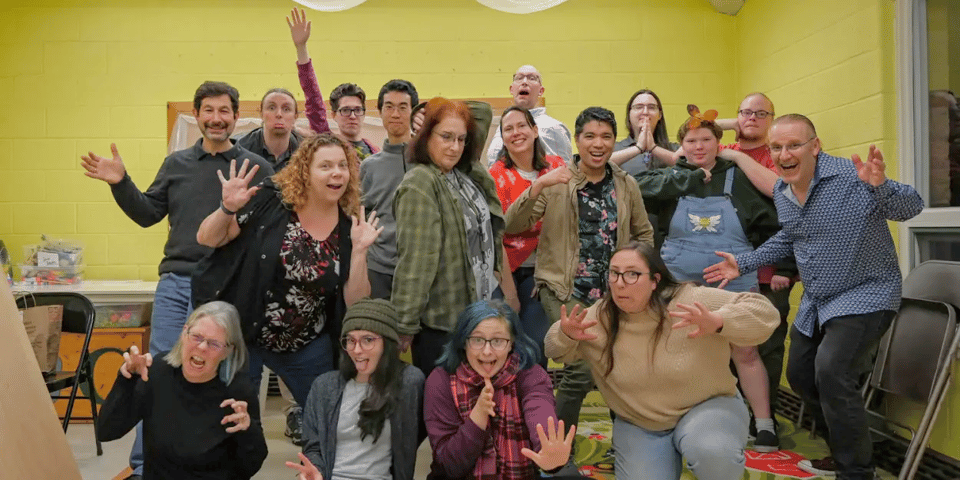 A group of ~20 people in a photo, making silly faces and poses