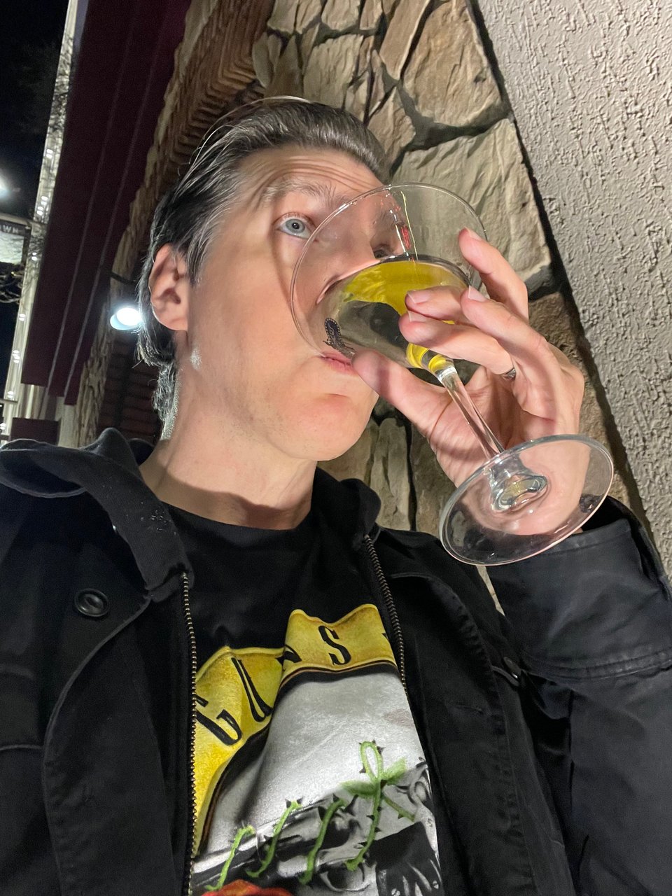 A human man sipping a martini outside with dramatic uplighting