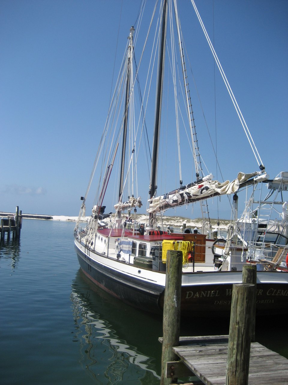 A docked schooner with a black and white hull, the sails furled.