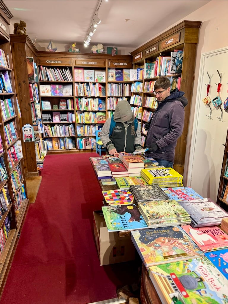 A boy and his father look at  books to purchase in a book shop.