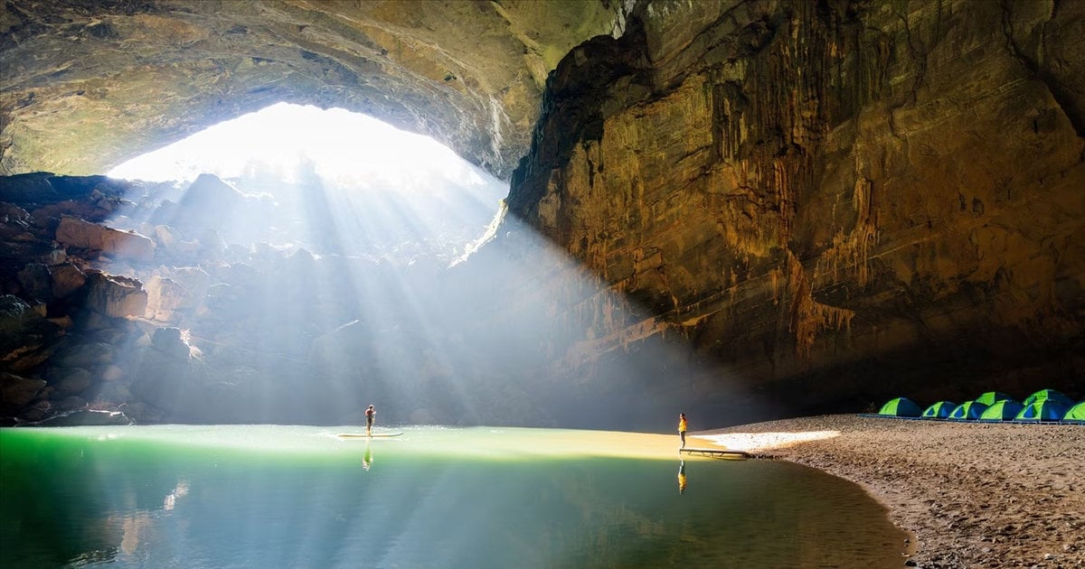 Sunlight pours through a collapsed skylight onto an underground lake and campsite in Hạng Sơn Đoòng. From dantocphattrien.vietnamnet.vn.