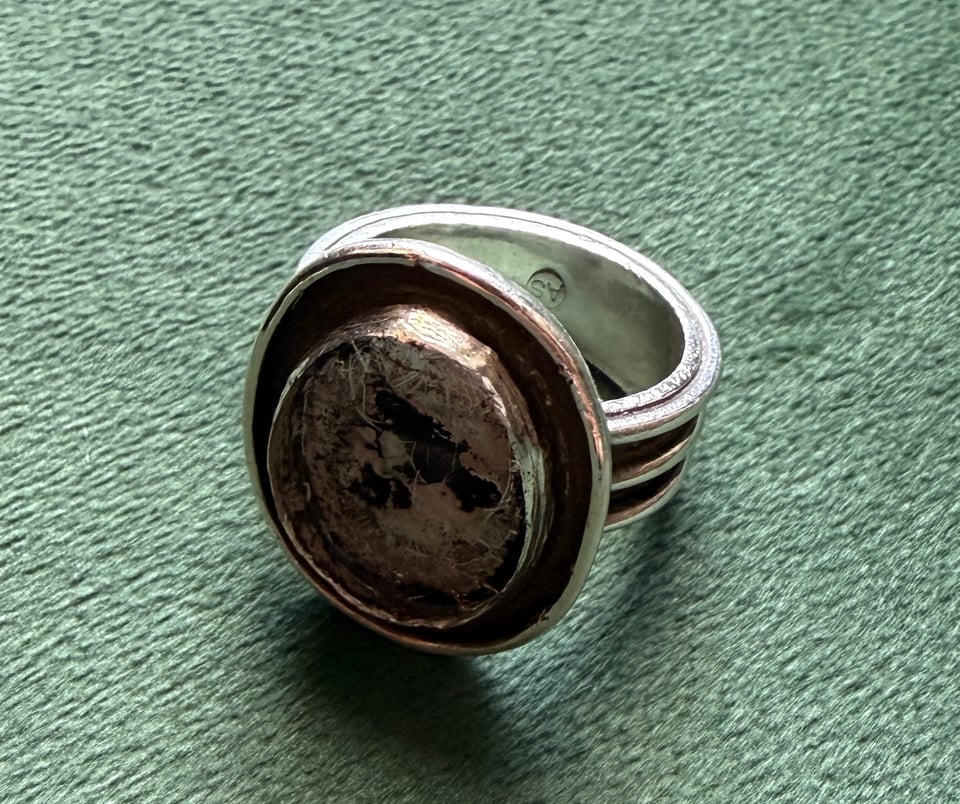 silver ring with an empty bezel where a silver eye stone used to be