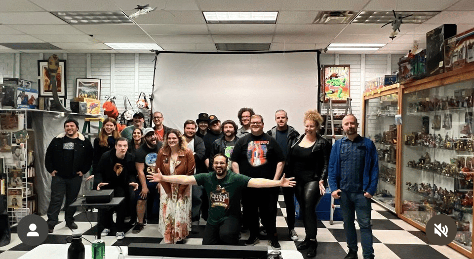 A group of filmmakers pose in front of a makeshift screen in a toy store