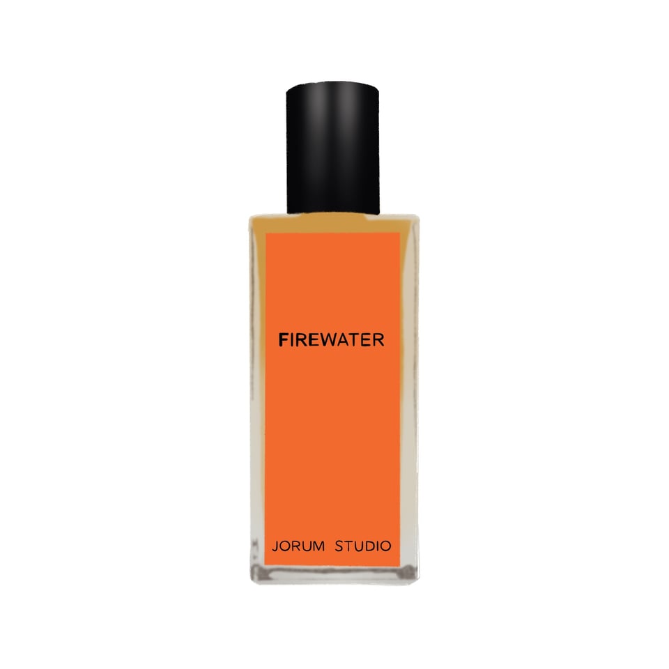 A bottle of Firewater by Jorum Studio. It has golden liquid inside, with a shiny black cap. The label is bright, rich orange and has black print on it.