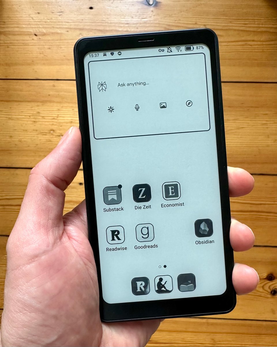 a hand holding a smartphone with an eInk display