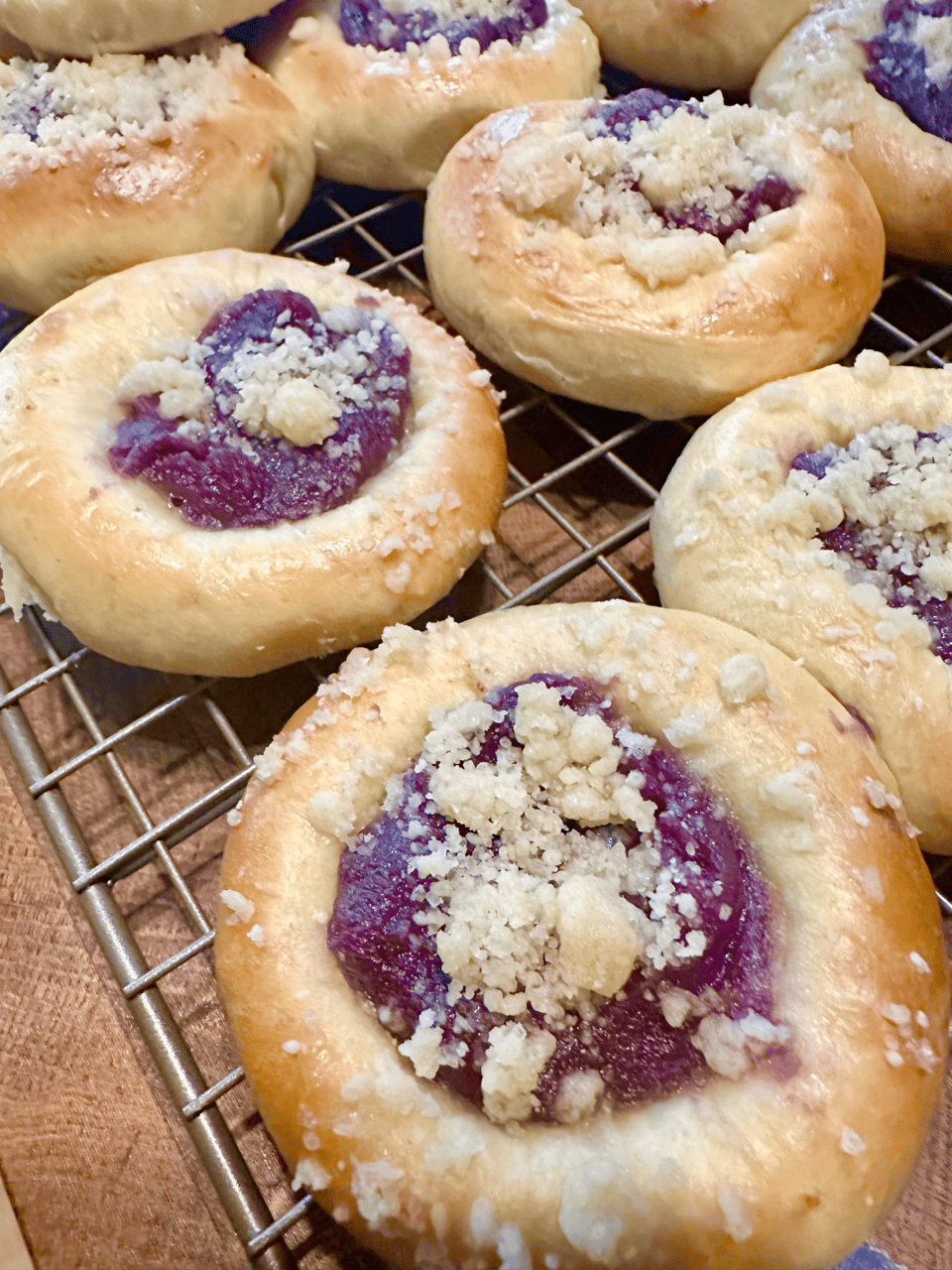 a closeup of a few ube-filled kolache pastries cooling on a rack