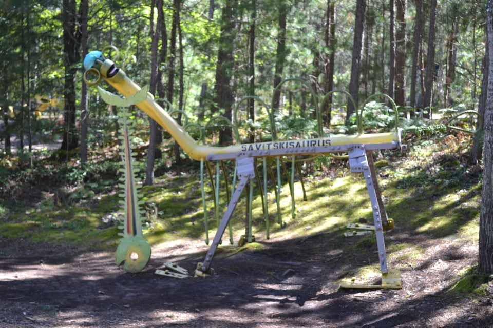 A weird monster made out of pipes and metal in the middle of the woods. It is labeled 'Savitskisaurus"