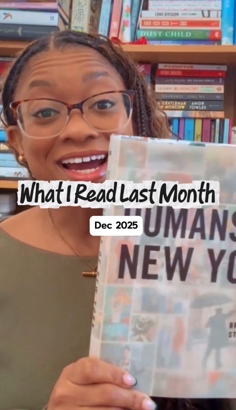 Me smiling at the camera in front of a bookshelf, holding a copy of Humans of New York. Overlaid text reads “What I Read Last Month” with a label underneath saying “Dec 2025.”