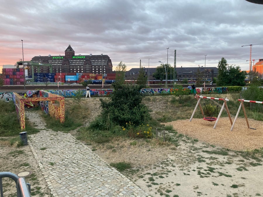 Urban park during sunset with swings, plants, graffiti
