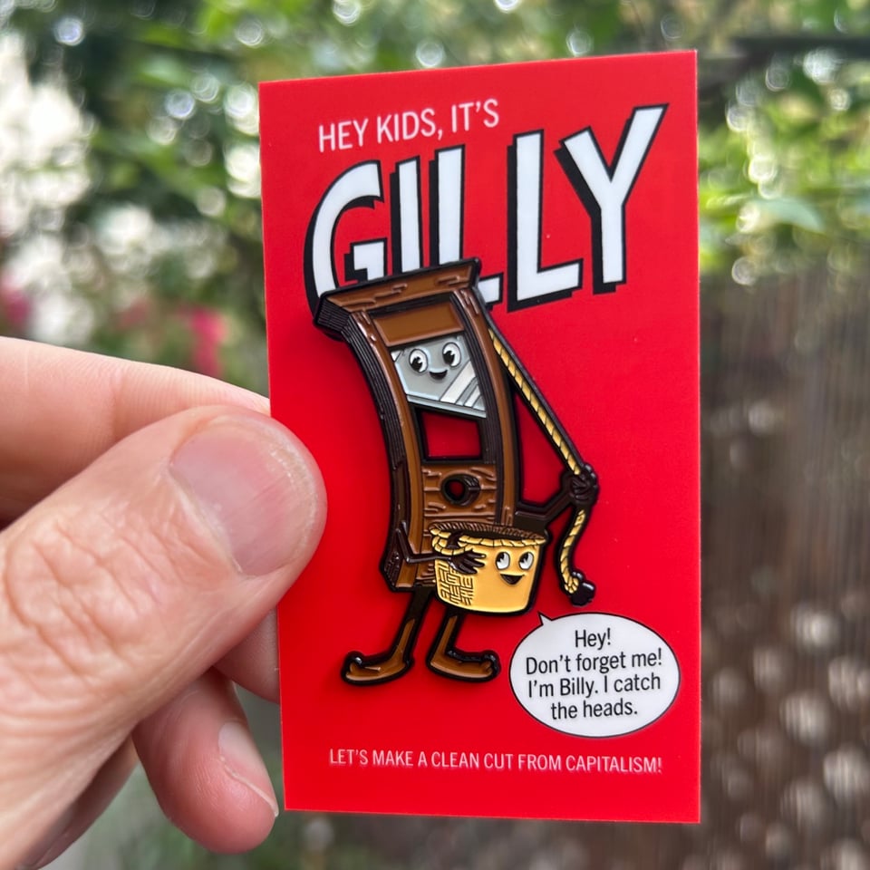 My enormous thumb holding a red card with an anthropomorphic guillotine enamel pin. Her name is Gilly. Say her name.