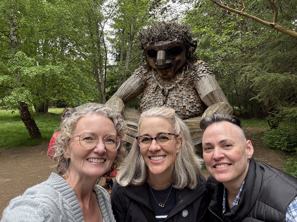 Three people standing in front of a wooden troll statue on Bainbridge Island in Washington.
