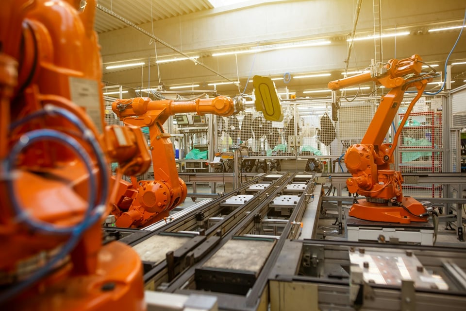 Orange factory robots in action. Photo by Simon Kadula on Unsplash.