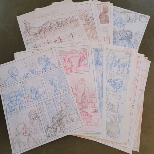 A photo of several physical penciled pages from The Last Band On Earth issues 1 and 2, piled up and fanned out on a table.