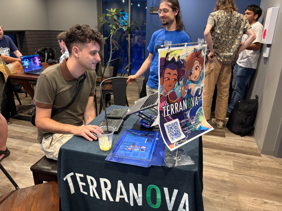 A person playing on a laptop computer at a booth with the words that say, "Terranova." The person is smiling as they play.