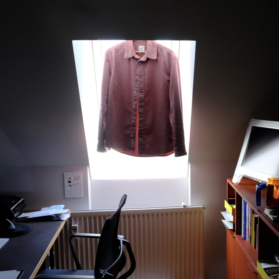 photo of a shirt on a hanger in front of the window, blocking most of the light coming in