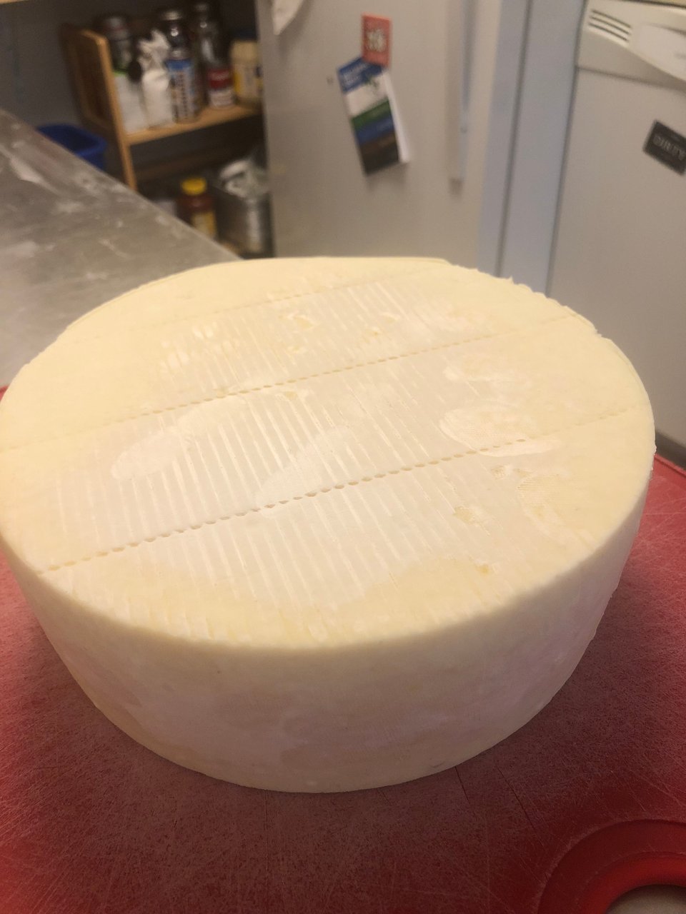 a large round of white cheese sitting on a red cutting board