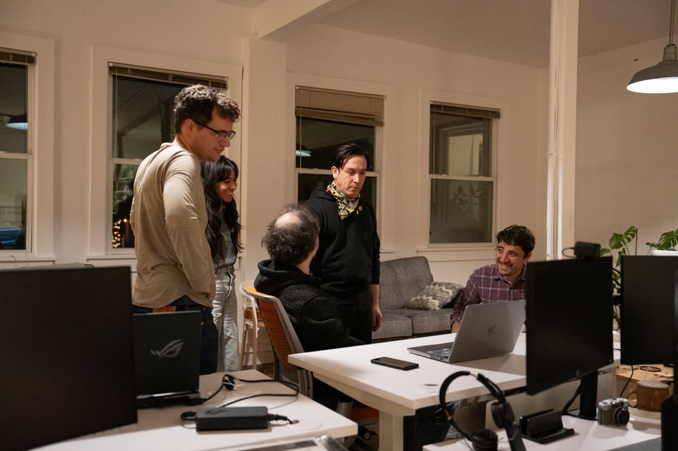 A group of people standing around a screen.