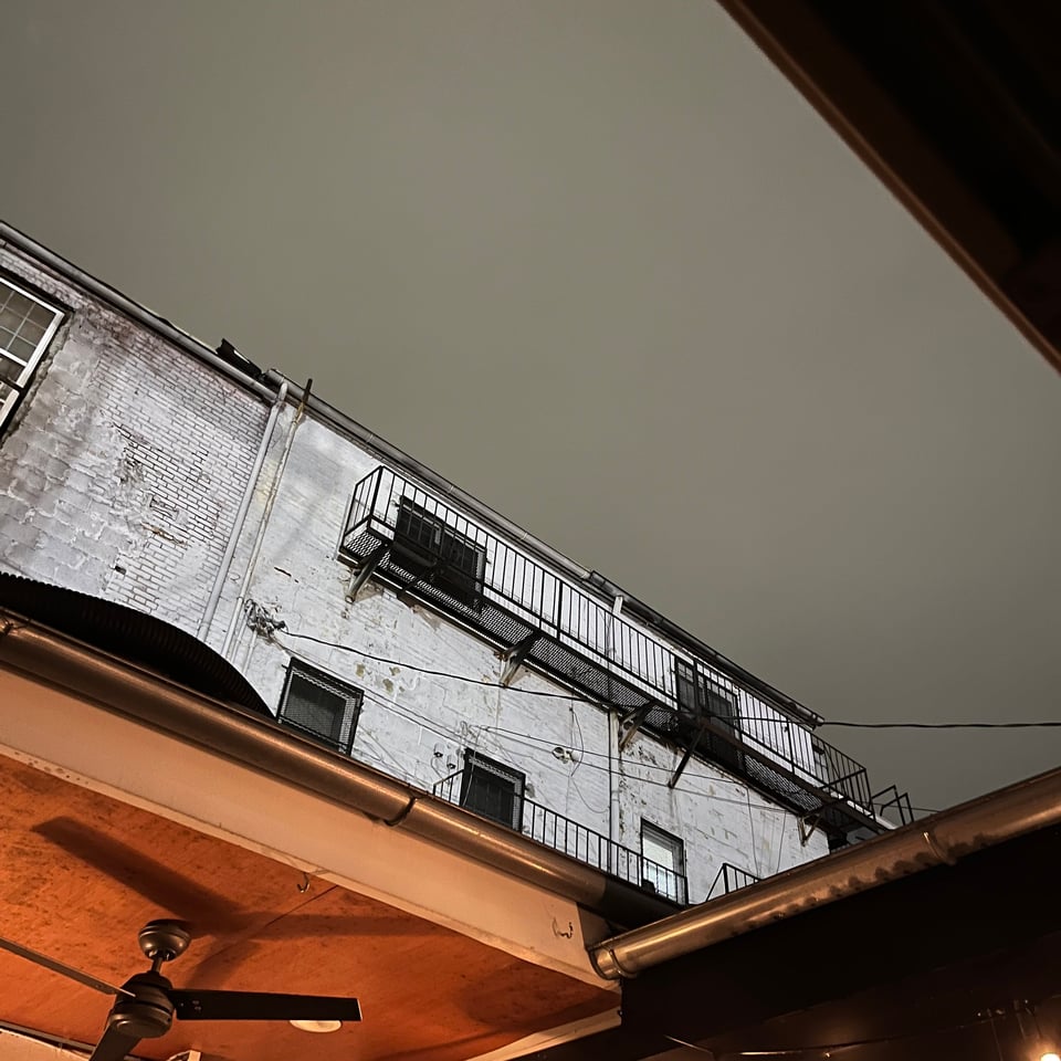 A view of a cloudy sky and a white brick building from the open roof of a concert space in Baltimore.