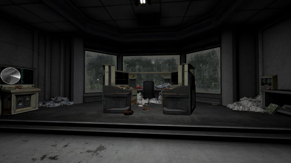 Big office with a U-shaped desk in the middle, piles of paper litter corners of the room. On the desk there are several monitors, and an empty chair.