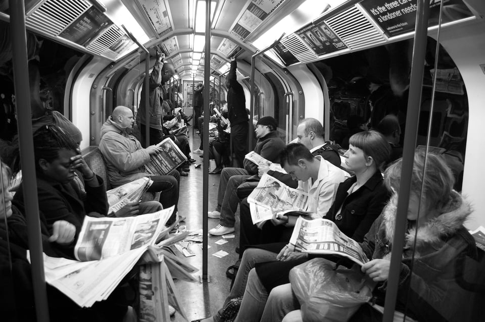 side a London Underground ("Tube") carriage, which shows many people reading newspapers. Photo by Peter Lawrence on Unsplash.