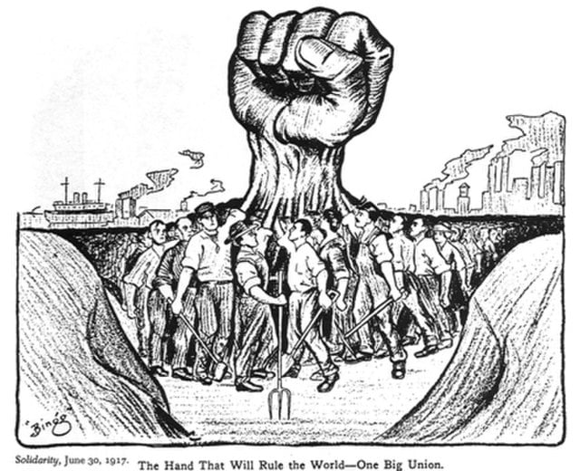 Cartoon depicts a crowd of workers gathered, with those at the forefront raising their fists, which combine into one large raised fist. In the background are factories and a ship. The image is captioned: "The Hand That Will Rule The World - One Big Union."