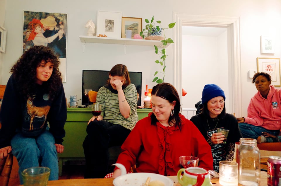 Five seated people cringe and look away from something out of frame