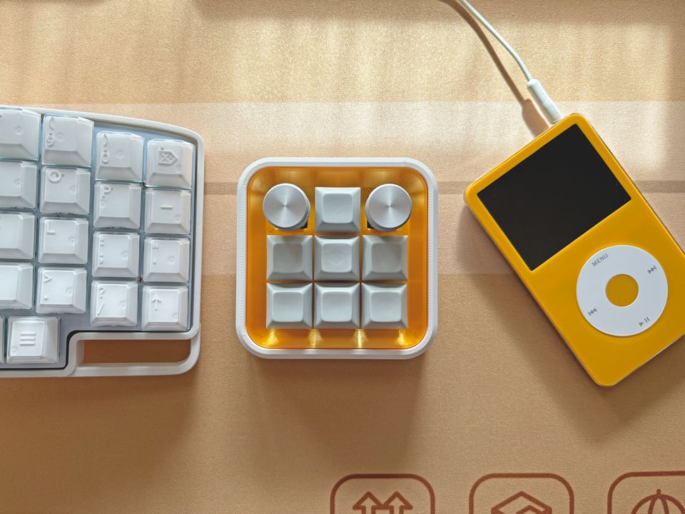 Photo of the Banchan macropad, a 3x3 key macropad with a white case and yellow plate