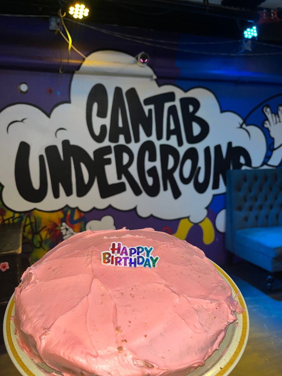 Happy Birthday cake in front of the Cantab Mural