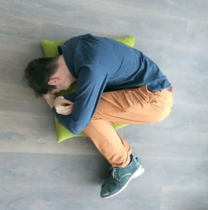 Anton lying on the floor hugging his knees
