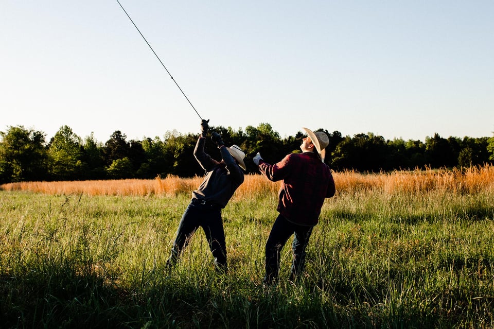 two people holding a hot air balloon rope in a field
